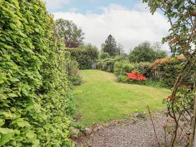 a garden with a large hedge and a green yard at Grisedale View in Keswick