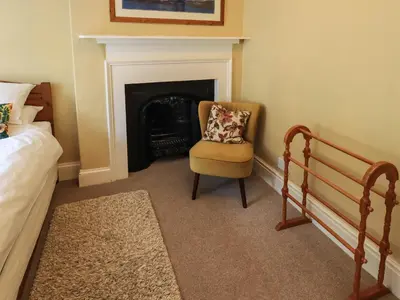 a bedroom with a chair and a fireplace at Sandburne Cottage in Keswick