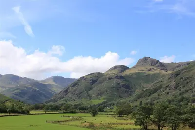 a green field with mountains in the background at Mellbreak in Chapel Stile