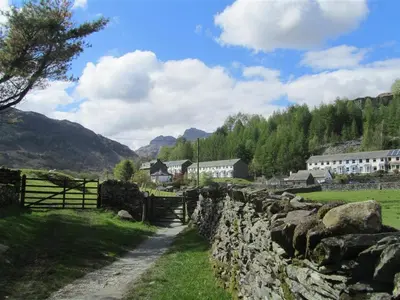 a stone wall and a field with houses and a fence at Mellbreak in Chapel Stile