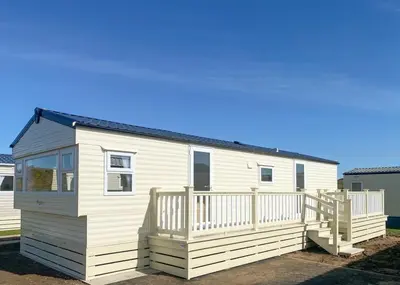 a white tiny house with a large deck at Burrowhead Holiday Village in Isle of Whithorn
