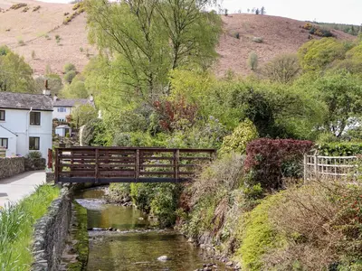 a wooden bridge over a river in a small town at Holme Rigg in Keswick