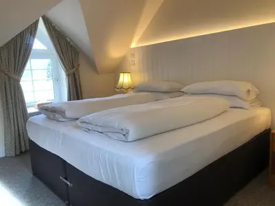 a bedroom with two beds with white sheets and a window at Glenheurie Cottage in Polmood