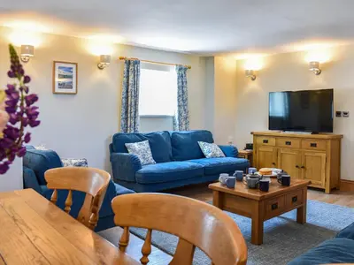 a living room with a blue couch and a tv at The Old Workshop in Keswick