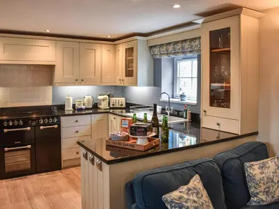 a kitchen with white cabinets and a black counter top at The Old Workshop in Keswick