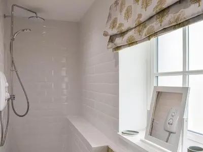 a white bathroom with a shower and a window at The Old Workshop in Keswick