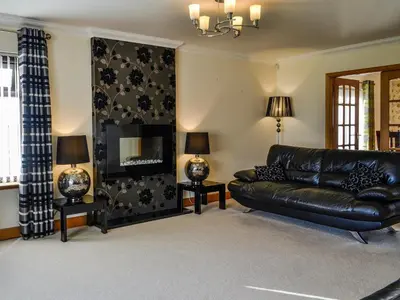 a living room with a leather couch and a fireplace at Ashgrove in Mainsriddle