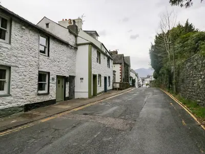 an empty street in a village with white houses at Latch Cottage in Keswick