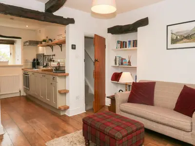 a living room with a couch and a kitchen at Latch Cottage in Keswick