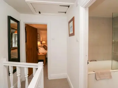a bathroom with a bath tub and a staircase at Latch Cottage in Keswick