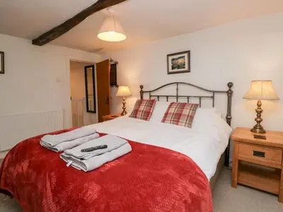 a bedroom with a large white bed with a red blanket at Latch Cottage in Keswick