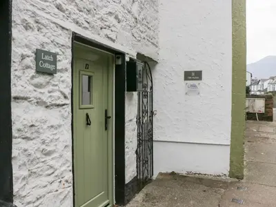 a green door on the side of a white building at Latch Cottage in Keswick