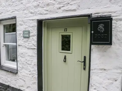 a door on a stone building with a sign on it at Latch Cottage in Keswick
