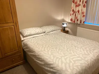 a small bedroom with a bed with white sheets at Cosy home near hospital in Carlisle