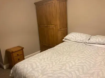 a bedroom with a bed and a wooden cabinet at Cosy home near hospital in Carlisle