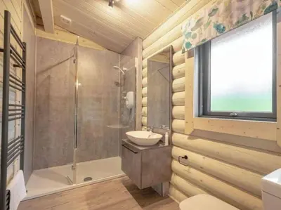 a bathroom with a shower and a sink and a toilet at Treetops Luxury Log Cabin - Hot tub, BBQ & Sauna in Kippford