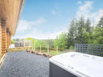 a bathroom with a tub and a view of a yard at Treetops Luxury Log Cabin - Hot tub, BBQ & Sauna in Kippford