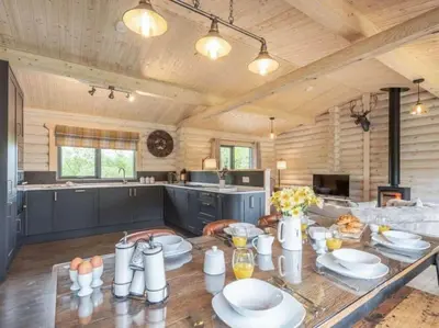 a large kitchen with a table with plates on it at Treetops Luxury Log Cabin - Hot tub, BBQ & Sauna in Kippford