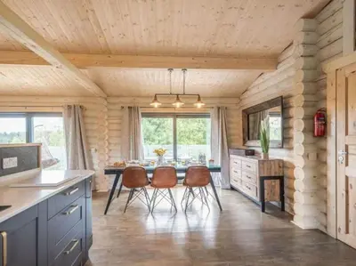 a kitchen with a dining room table and chairs at Treetops Luxury Log Cabin - Hot tub, BBQ & Sauna in Kippford