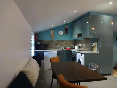 a kitchen with a table and a kitchen with blue walls at John Collingwood, Bowness-on-Solway ideal for starting of finishing a walk along Hadrians Wall in Bowness-on-Solway