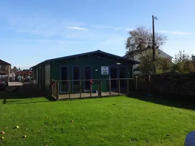 a green building with a fence in a yard at Sians Retreat, Bowness on Solway, perfect stop over when walking Hadrians Wall with hot tub in Bowness-on-Solway