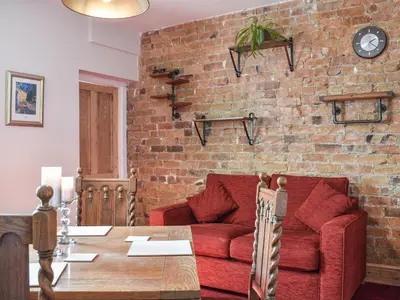 a living room with a red couch and a brick wall at Long Rose in Keswick