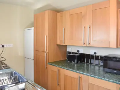 a kitchen with wooden cabinets and a white refrigerator at Long Rose in Keswick