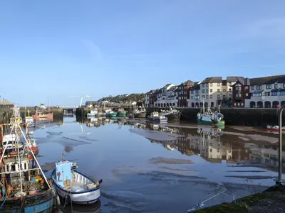 a group of boats docked in a river with buildings at Harbour Watch in Maryport