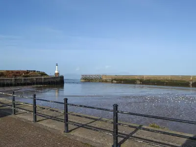 a body of water with a pier and a lighthouse at Harbour Watch in Maryport