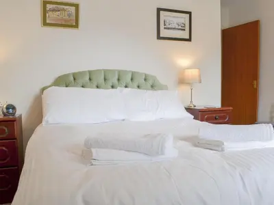 a white bed with white pillows and a green headboard at Harbour Watch in Maryport