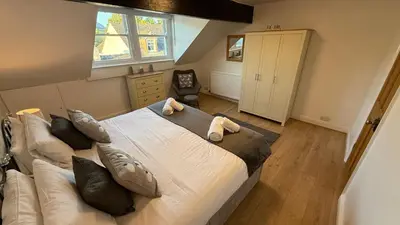 a bedroom with a large white bed and a chair at Ridge View - Amazing Roof Terrace in Keswick