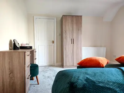 a bedroom with two beds and a wooden cabinet at Grove House in Egremont