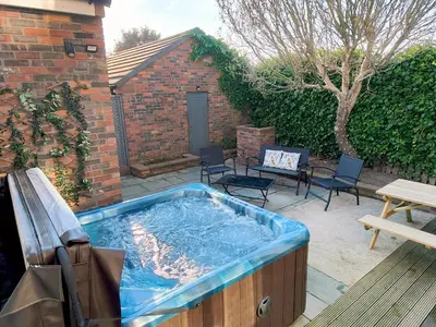 a hot tub in a backyard with chairs and a table at Grove House in Egremont