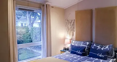 a bedroom with a bed with blue pillows and a window at 24 The Zen Den Cumbria in High Hesket