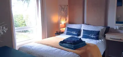 a bedroom with a bed with blue pillows and a window at 24 The Zen Den Cumbria in High Hesket