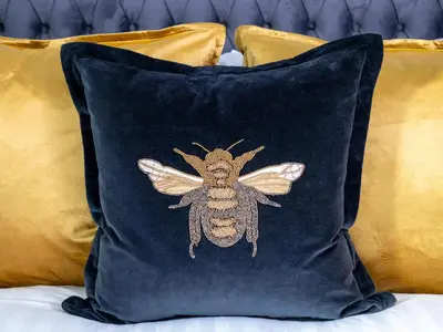 a bee applique on a blue pillow on a bed at Apartment 1 Latrigg in Keswick