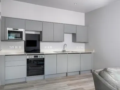 a kitchen with white cabinets and a sink and a couch at Apartment 2 Blencathra in Keswick