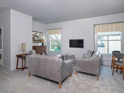 a living room with a couch and chairs and a tv at Apartment 2 Blencathra in Keswick