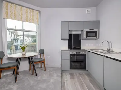 a kitchen with white cabinets and a table with chairs at Apartment 4 Skiddaw in Keswick