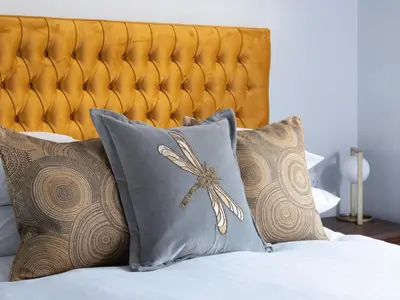 a bed with four pillows and a gold headboard at Apartment 4 Skiddaw in Keswick