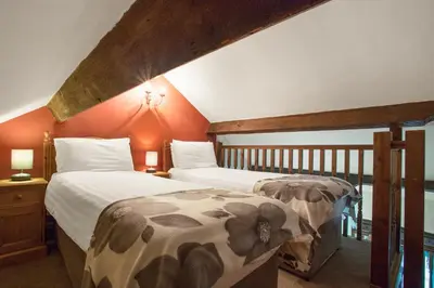 two beds in a room with orange walls at The Mountain Cottages - Carpenters in Coniston