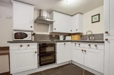 a kitchen with white cabinets and a microwave at The Mountain Cottages - Millrace in Coniston