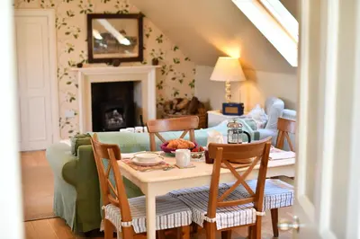 a living room with a table and chairs and a couch at Stables Cottage in Stranraer