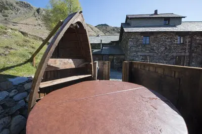 a wooden bench in front of a building at The Mountain Cottages - Pelton Wheel in Coniston