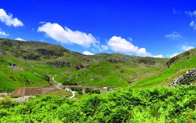 a view of a green mountain with a winding road at The Mountain Cottages - Pelton Wheel in Coniston