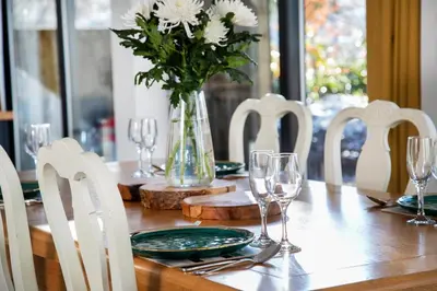 a table with white chairs and a vase with white flowers at Bird House - Sleep with the Owls! in Carlisle