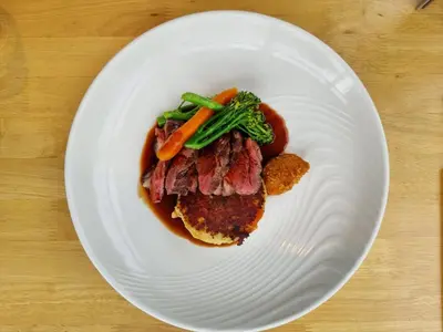 a plate of food with meat and vegetables on a table at The Old Mill Inn in Dearham