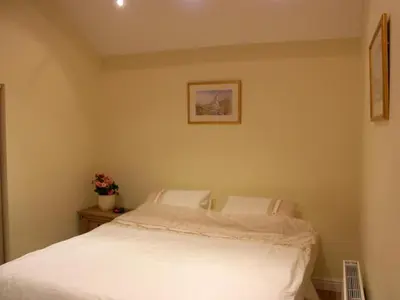 a bedroom with a white bed and a picture on the wall at Pinfold Holiday Cottage in Laxey
