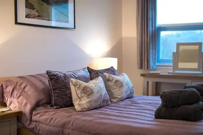 a bedroom with a bed with pillows and a window at Herdwick Place Langdale Valley in Great Langdale