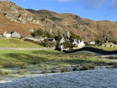 a group of houses in a field with a mountain at Herdwick Place Langdale Valley in Great Langdale